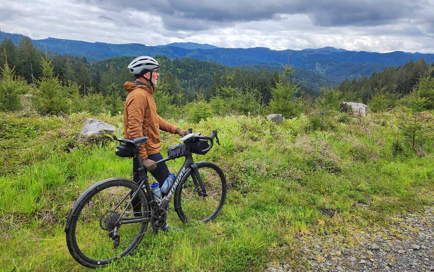 Photo of a cyclist on the Corvallis-to-the-Sea Trail surrounded by rolling green hills. Photo copyright Dan Shryock.