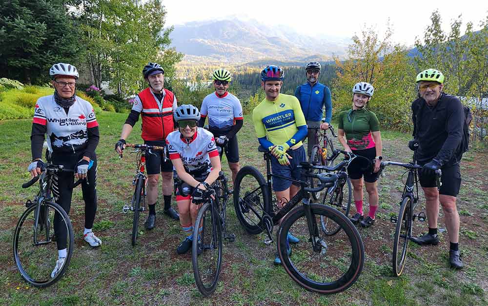 Photo of members of the Whistler Cycling Club posing with their bikes at Green Lake in Whistler, British Columbia.